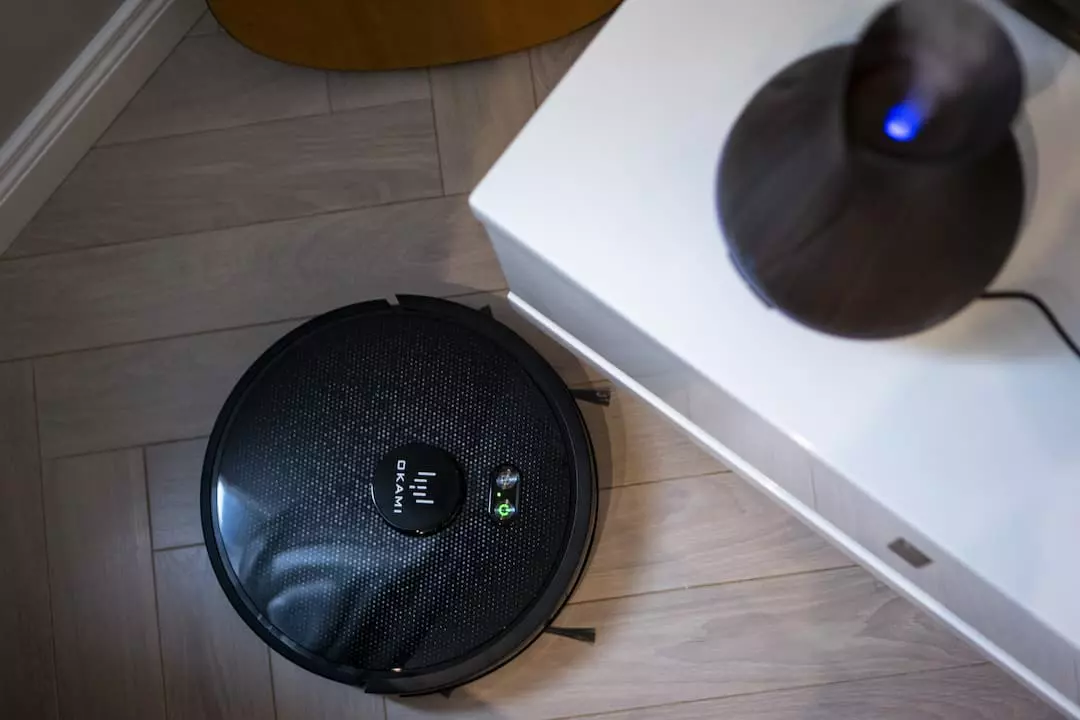 Робот-пылесос Okami на деревянном полу рядом с увлажнителем воздуха и белым шкафом