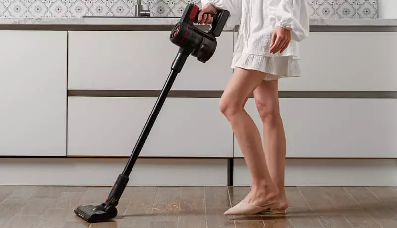Женщина использует беспроводной вертикальный пылесос Okami V300