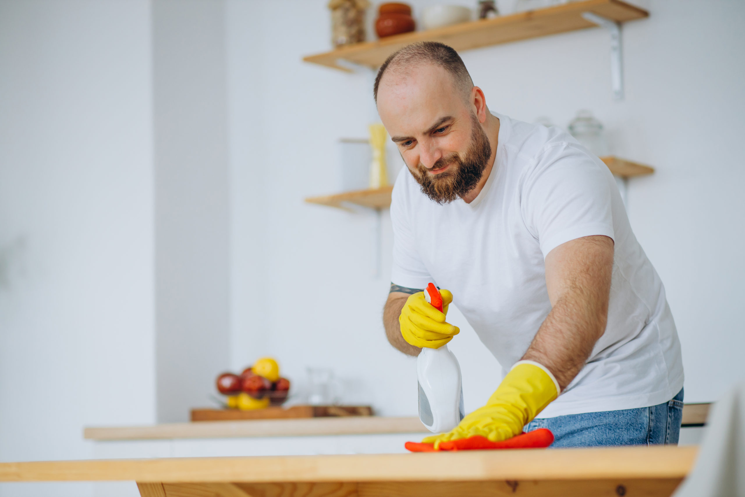 Man wearing rubber gloves cleaning up at the kitchen